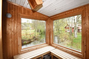 A cabin with wooden walls and large windows overlooking a river and forest. - StayNordic | Idyllic holiday house in Sundshult | SE09011 (Hedekas)