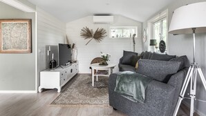 A modern living room with a grey sofa, white side table, and a small white table with a rug. - Fantastic cottage with panoramic views of Lake Vidöstern | SE06031 (Vittaryd)