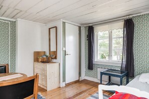 Une pièce comprenant une commode en bois, un miroir, une fenêtre avec des rideaux et une petite table.