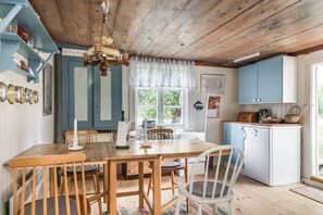 Une cuisine rustique avec des meubles en bois, une table à manger entourée de chaises et un luminaire suspendu.