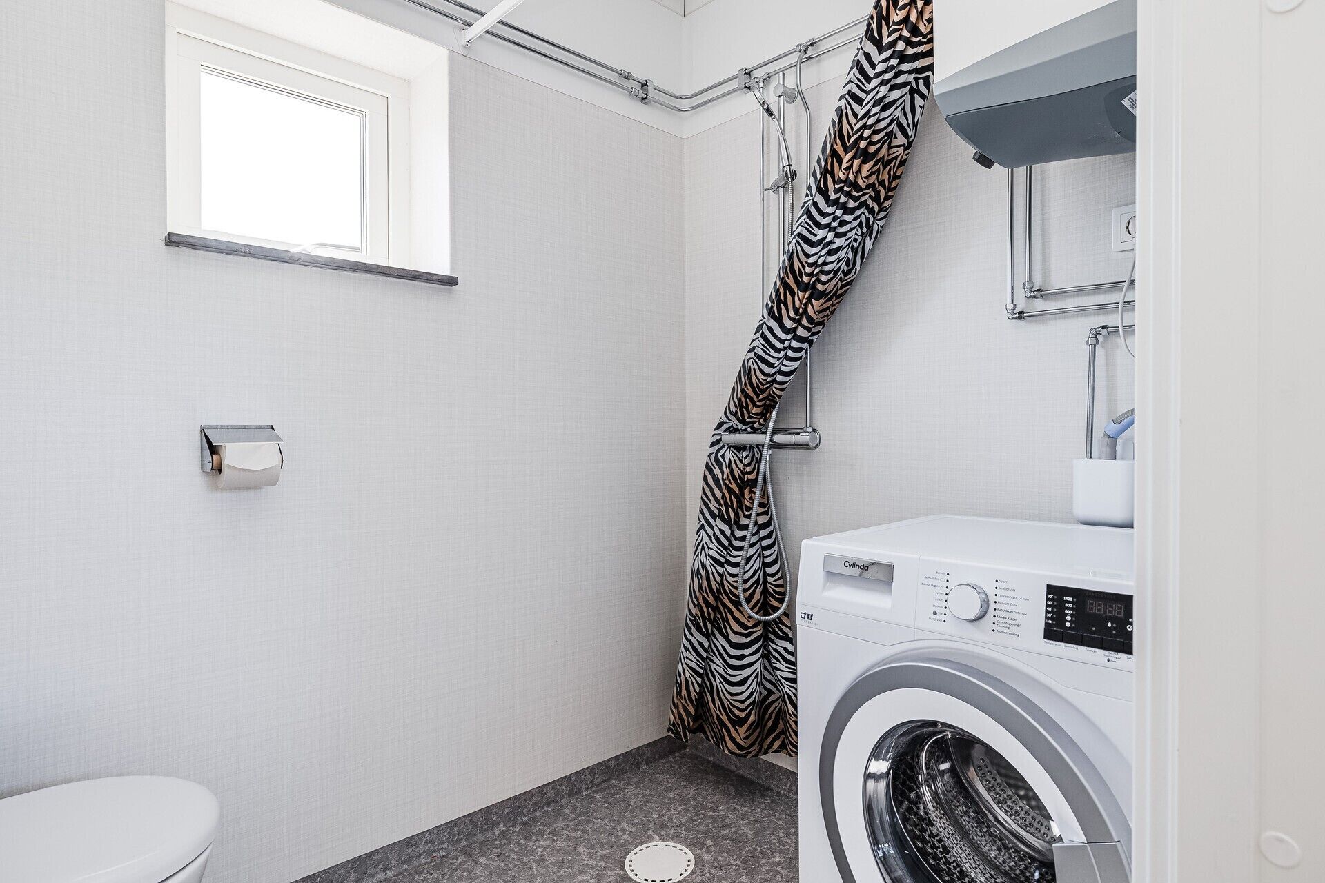 Un bagno compatto con doccia, WC e una lavatrice a carica frontale.