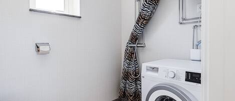 Un bagno compatto con doccia, WC e una lavatrice a carica frontale.