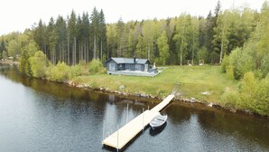 A lakeside cabin with a dock and a boat.