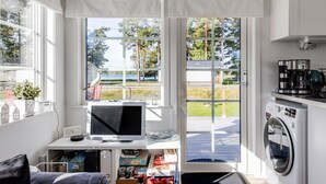 Cozinha compacta com máquina de lavar, computador e janela com vista para o exterior.