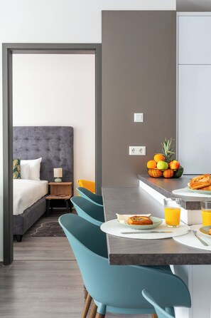 A modern hotel room with a bed, a small table with breakfast, and a fruit basket. - Hock Residence by Vagabond (Budapest)