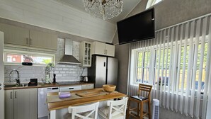 A modern kitchen with white cabinets, a wooden countertop, a built-in stove, and a large window with blinds.