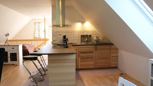 A kitchen with a bar area, wooden cabinets, and a window. - Functional and cozy studio at Abbekås Golf Course | SE01024 (Abbekås)