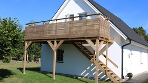 A two-story house with a wooden deck, a staircase, and a white exterior. - Functional and cozy studio at Abbekås Golf Course | SE01024 (Abbekås)
