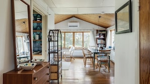 A spacious room with a high ceiling, wooden flooring, a dining area with chairs and a table, and a large window providing natural light. - Nice holiday home near Skummelövs strand | SE02049 (Skummeslövsstrand)