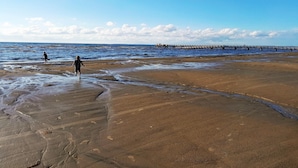 A beach with a pier extending into the water, sandy shore, and footprints in the sand. - Nice holiday home near Skummelövs strand | SE02049 (Skummeslövsstrand)