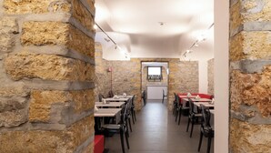 A restaurant with stone walls, tables, chairs, and a bar area. - Hotiday Room Collection - Palermo Politeama (Palermo)