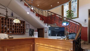 A reception area with a wooden desk, a YASHI monitor, a staircase with red railings, and a stained glass window. - Hotiday Room Collection - Palermo Politeama (Palermo)