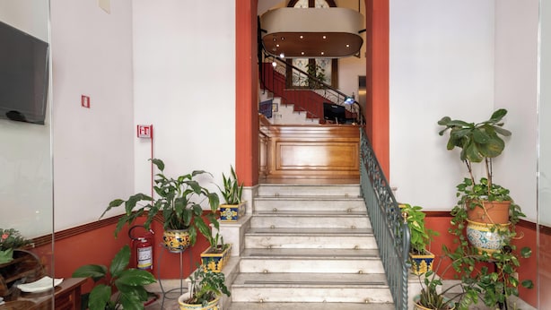 A staircase with marble steps, a red archway, and potted plants on either side. - Hotiday Room Collection - Palermo Politeama (Palermo)
