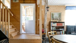 A wooden interior with a staircase leading to a door, a bookshelf, and a table with chairs. - Rural holiday home in Sjöared | SE02024 (Markaryd)