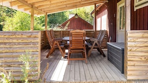 A wooden deck with a table and chairs, a hot tub, and a wooden fence. - Rural holiday home in Sjöared | SE02024 (Markaryd)