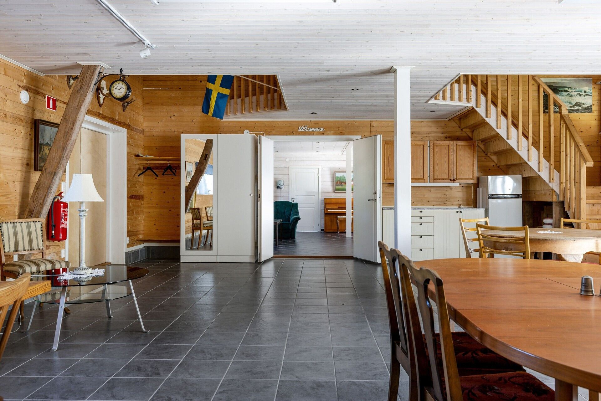 A wooden interior with a dining area, kitchen, and a staircase.