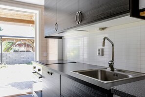A modern kitchen with stainless steel appliances, a built-in sink, and a window overlooking a garden. - Rural holiday home in Sjöared | SE02024 (Markaryd)