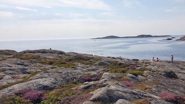 Paisaje costero rocoso con vista al mar y islas distantes.