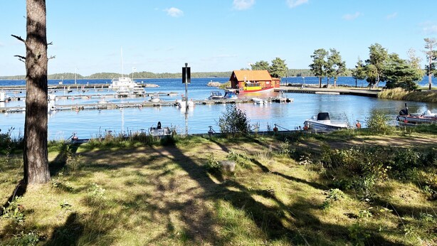 Un port de plaisance avec des bateaux, un bâtiment rouge et un ciel bleu clair.