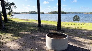 Un bac à fleurs en béton, placé dans un environnement naturel avec vue sur un lac.