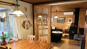 Un intérieur en bois comprenant une table à manger, des chaises, un canapé, un téléviseur et un coin cuisine avec des placards et un réfrigérateur.