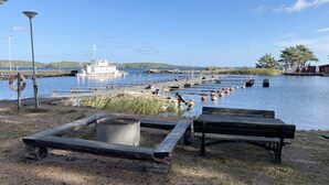 Une zone au bord du lac, aménagée avec des bancs en bois, un barbecue et une jetée où sont amarrés des bateaux.