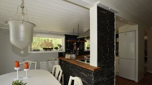 A modern kitchen with a stone accent wall, white cabinetry, and a dining area with a white table and chairs.