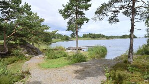 A gravel path leading to a dock by a lake with trees and greenery around.