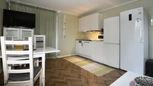 A compact kitchen with white cabinets, a built-in microwave, and a refrigerator.