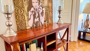 A wooden console table with a large framed artwork above it, two glass candle holders, and a small white vase with a blue handle. - L'appartement Nicolo (Paris)