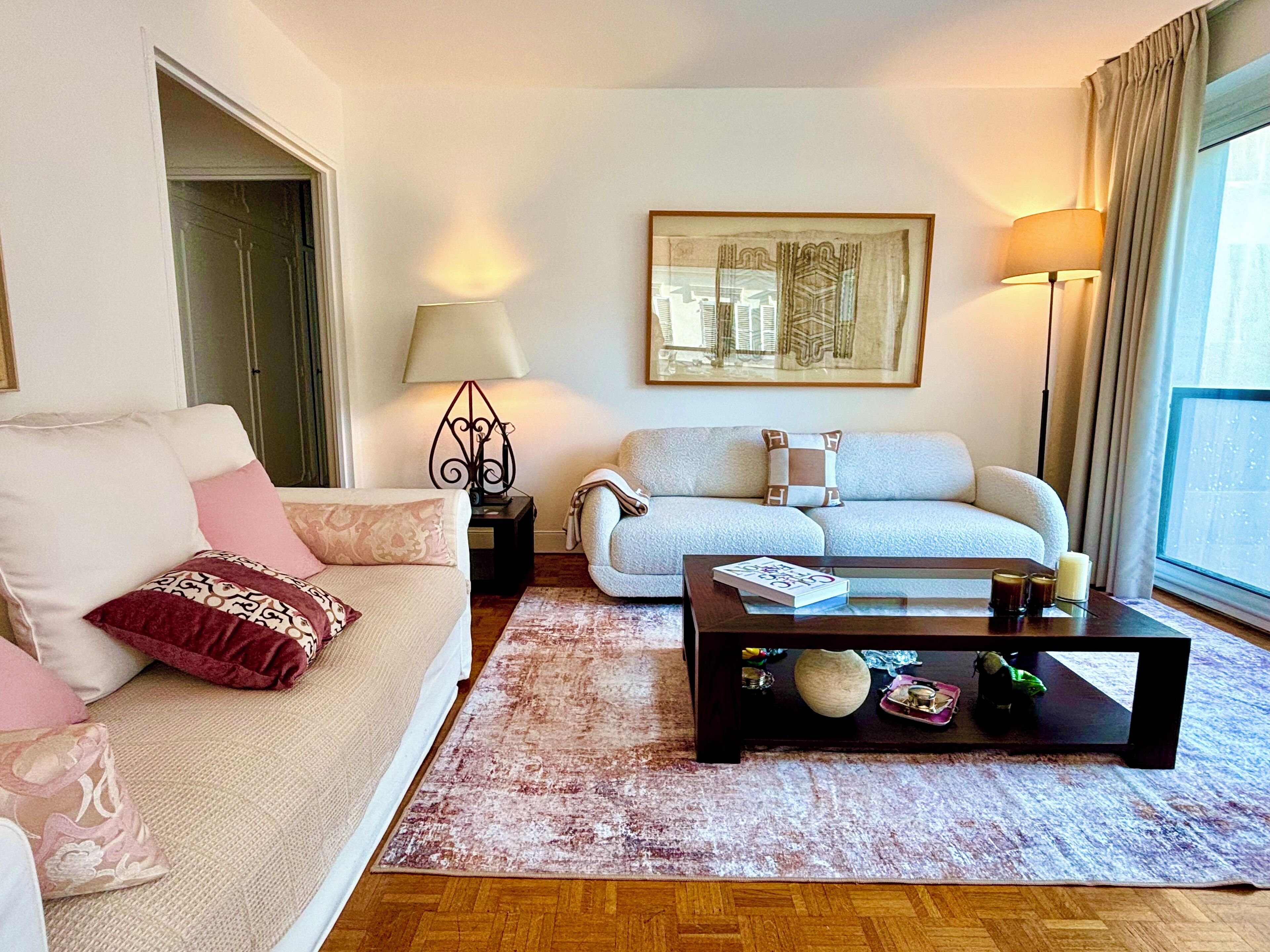 A living room with a sofa, a coffee table, a lamp, and a painting on the wall.
