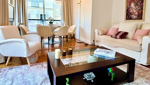 A modern living room with a glass coffee table, white sofas, and a dining area with chairs and a table set for four. - L'appartement Nicolo (Paris)