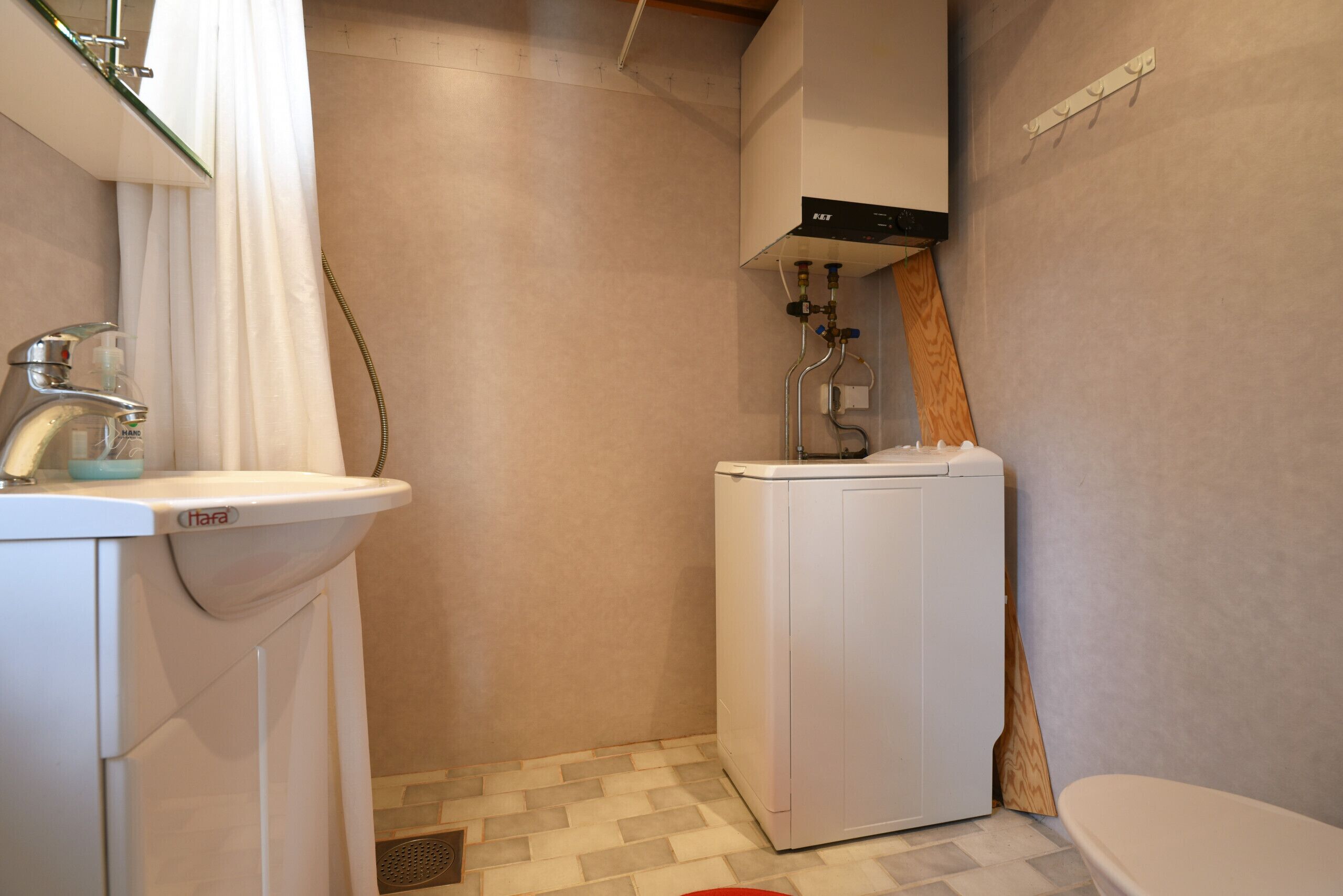 Ett litet badrum med handfat, tvättmaskin och toalett.