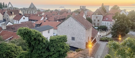 Una vila amb edificis de pedra històrics, una església destacada i una vista del mar al capvespre.