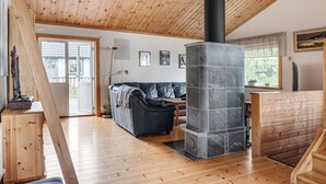 A wooden interior with a stone fireplace, a sofa, and a dining area.