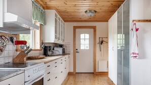 A kitchen with a wooden ceiling, white cabinets, a stove, and a coffee maker.