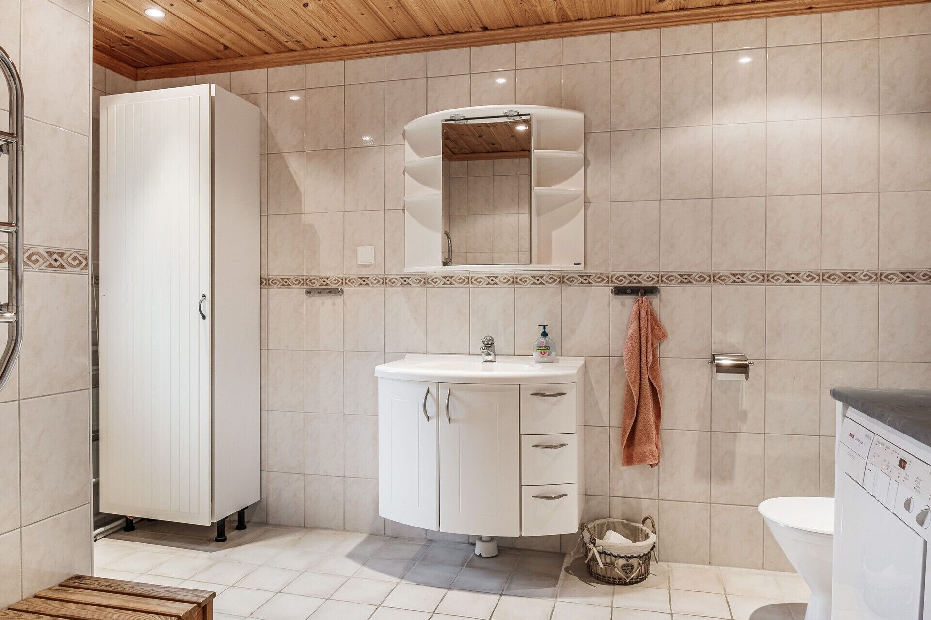 A modern bathroom with a white sink, mirror, and toilet.