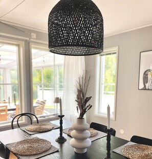 A dining area with a table set for a meal, featuring a vase with dried foliage and a candle.