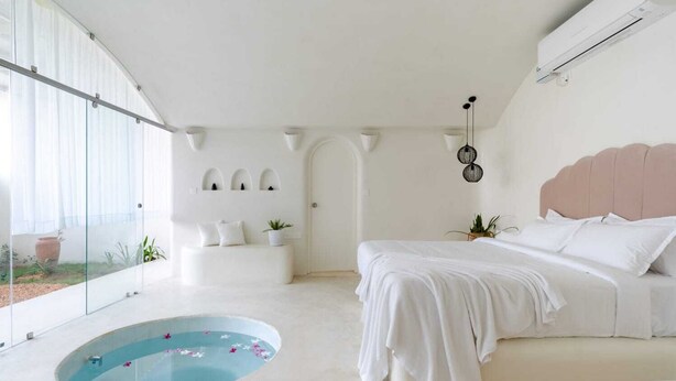 A modern bedroom with a large bed, a glass-enclosed pool, and a balcony with potted plants. - Nomads Resort - Destination Stays (Vanur)
