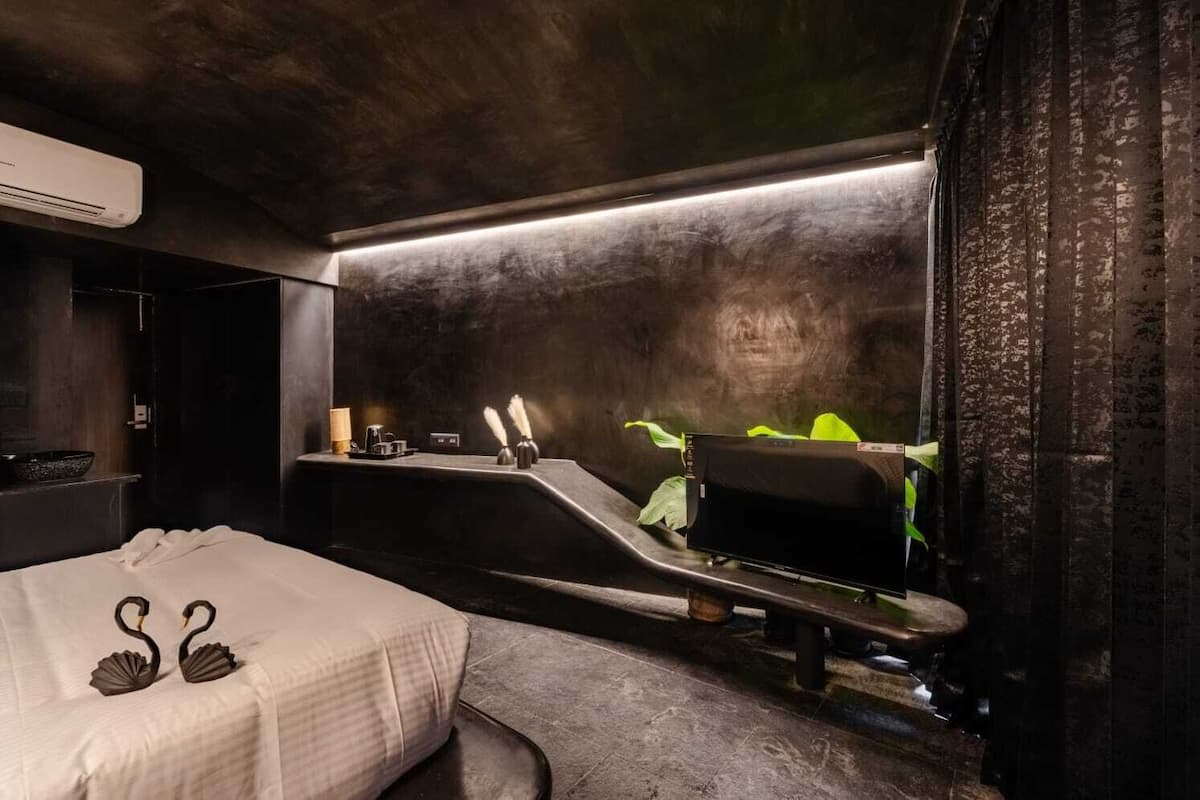 Un baño moderno con un espejo grande, una encimera negra, un lavabo y una zona de ducha.