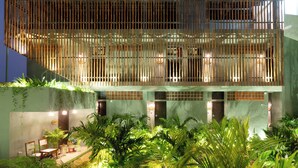 A modern building with a bamboo facade, multiple levels, and a well-lit entrance area with plants. - Nomads Resort - Destination Stays (Vanur)
