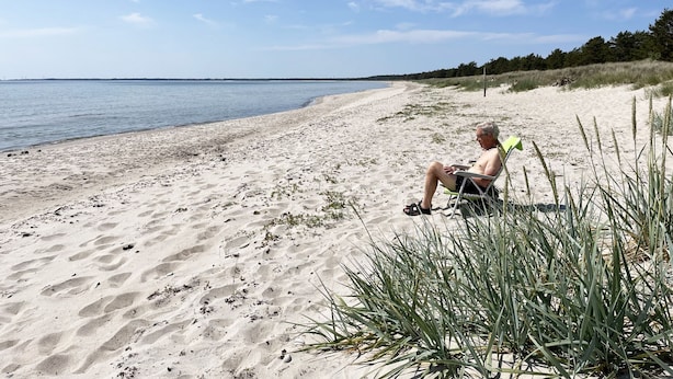 A beach with a person seated on a chair, a sandy shore, and a clear sky. - Nice cottage located in the north of Öland next to Byxelkrok | SE04024 (Byxelkrok)