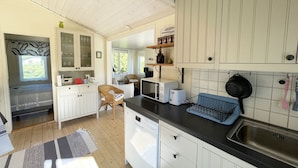 A compact kitchen with white cabinets, a black countertop, a microwave, a toaster, and a sink. - Nice cottage located in the north of Öland next to Byxelkrok | SE04024 (Byxelkrok)