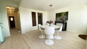A modern dining area with a round table, white chairs, and a chandelier.