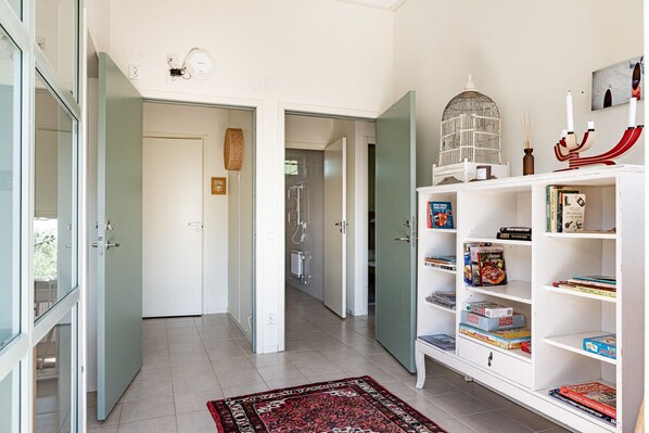 Un pasillo con puertas abiertas que dan a un baño y una sala de estar.