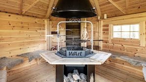 Ein Holzblockhaus-Innenraum mit Kaminofen, Schornstein und Fenster.