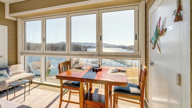 A dining area with a wooden table and chairs, large windows with a view of a lake and mountains, and a cozy seating area with a sofa and armchairs. - Top-floor Balcony & Serene Views: Huddleston Condo (Huddleston)
