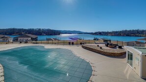 A swimming pool with a glass enclosure, a waterfront view, and a small building with a sign. - Top-floor Balcony & Serene Views: Huddleston Condo (Huddleston)