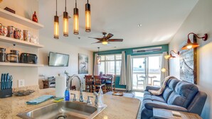 A modern kitchen with a sink, countertop, and overhead lighting. There is a dining area with a table and chairs. - Top-floor Balcony & Serene Views: Huddleston Condo (Huddleston)