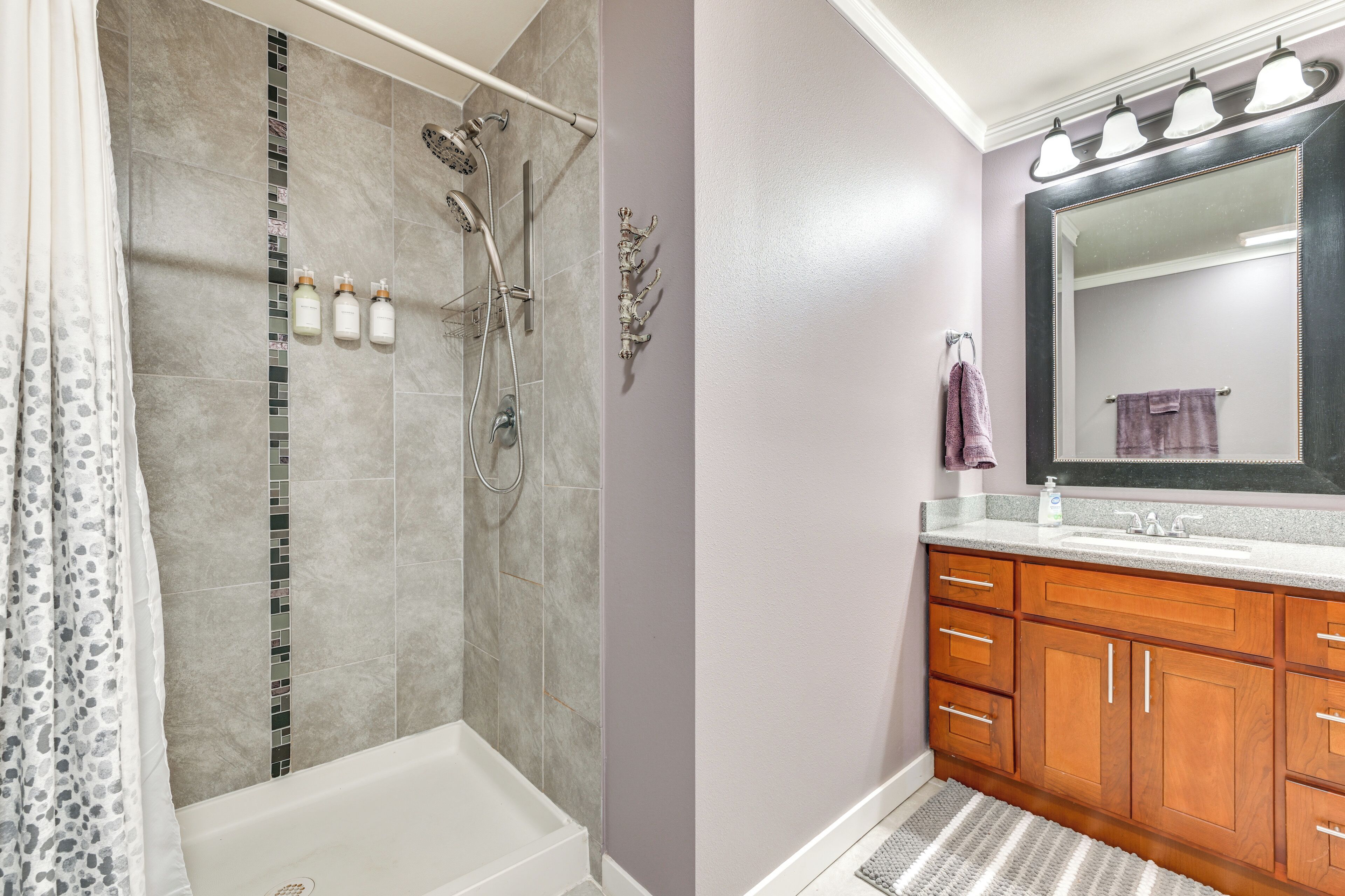 A bathroom with a shower, a bathtub, wooden cabinets, a vanity with a mirror, and a towel rack.